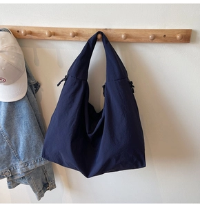 Detail of navy blue nylon tote bag hanging with casual denim jacket and baseball cap