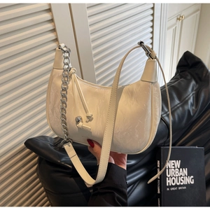 Detail of off-white crescent bag with textured leather and silver chain strap