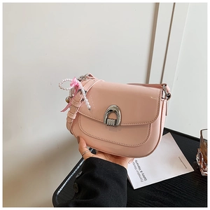 Détail du sac selle en cuir verni rose avec breloque perle et boucle argentée en forme de U