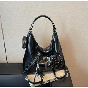 Detail of black glossy tote bag featuring silver stud M logo and contrast stitching