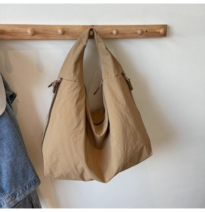Detail of khaki oversized canvas dumpling bag with zip closure on a wooden rack