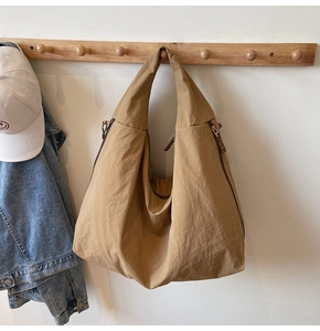 Detail of khaki nylon crescent bag showing durable zipper and spacious pleated texture