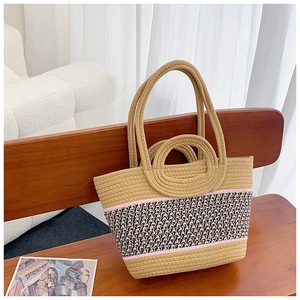 Detail of woven straw beach bag featuring tricolor striped patterns on a wooden chair