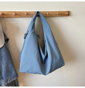 Detailed view of the gray-blue oversized hobo bag hanging on a wooden hook