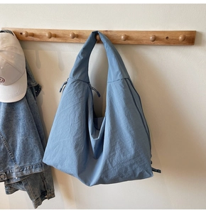 Close-up of blue hobo canvas shoulder bag with zipper and drawstring details hanging