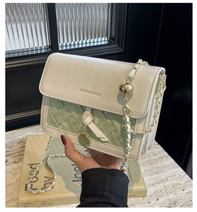 Détails de la texture tissée verte du sac bandoulière avec chaîne dorée et perle