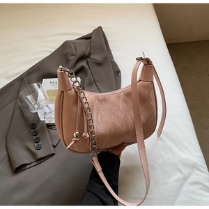 Detailed view of pink half-moon bag with marble texture, metal chain, and leather strap