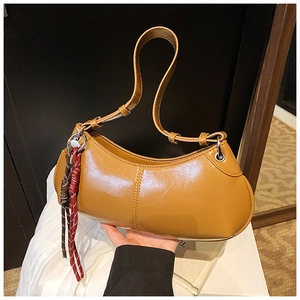 Detail of a brown oil-wax leather hobo bag with tricolor woven rope charm decoration