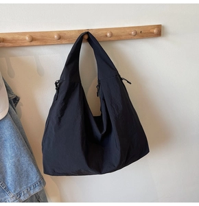 Detail of a black canvas tote bag with drawstring texture hanging on a wooden hook