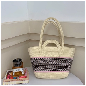 Detailed close-up of woven straw tote bag with geometric stripes and dual handles