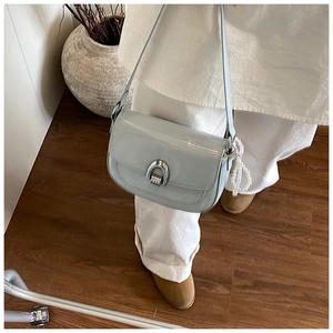 Détail du sac selle en cuir verni vert menthe avec boucle argentée et breloque perle