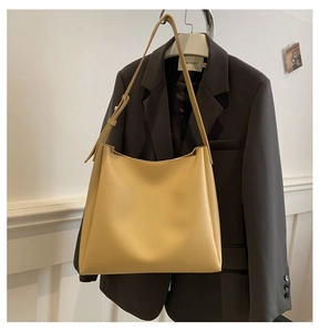 Détail du grand sac cabas en cuir PU crème avec bandoulière réglable sur un blazer