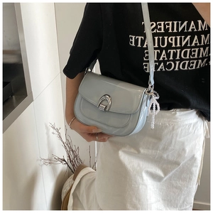 Détail du sac en cuir verni bleu clair avec boucle fer à cheval et breloque perle