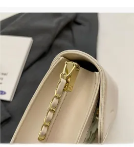 Détail de la chaîne dorée polie sur un sac bandoulière en cuir crème matelassé