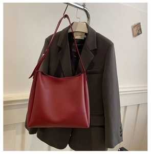 Détail d'un sac cabas bordeaux en cuir suspendu à côté d'un blazer gris pour un look bureau