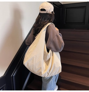 Close-up of lightweight off-white canvas tote bag with wide strap on stairs