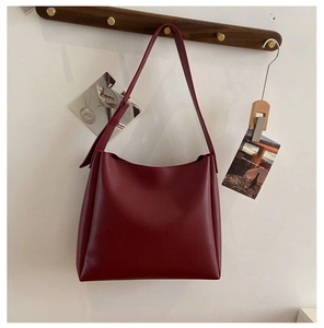 Détail du sac cabas en PU bordeaux suspendu à un crochet en bois au design minimaliste