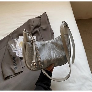 Detail of silver crescent moon bag with wrinkled texture, metal chain, and leather strap