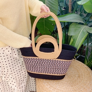 Macro detail of hand-woven straw tote bag with black and pink geometric wavy patterns