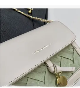 Détail du sac bandoulière tissé avec rabat en cuir beige et bandoulière chaîne décorée
