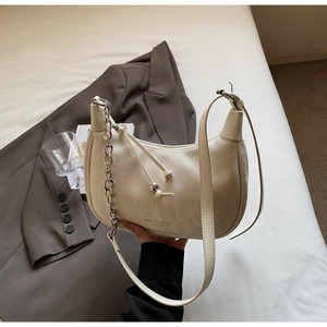 Close-up of a cream-colored half-moon bag featuring silver chain and brand logo detail