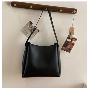 Sac fourre-tout en cuir PU noir suspendu à un crochet en bois dans un décor épuré