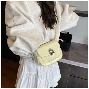 Détail du sac selle en cuir verni jaune avec breloques en perles blanches et fermoir en U