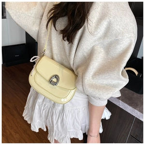 Détail du sac selle en cuir verni jaune avec boucle argentée et bandoulière perles