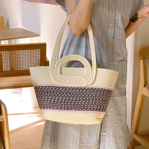 Detail of a large woven tote bag with three-color patchwork and dual shoulder straps
