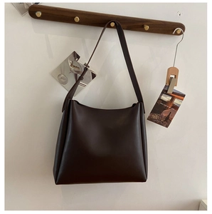 Détail du sac cabas vintage en cuir PU marron foncé sur un cintre en bois minimaliste