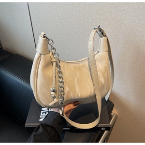 Detail of cream crescent bag with marble texture, silver chain and metal ball charm