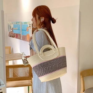 Detail of woven straw tote bag with black patterns and dual handles for beach vacation