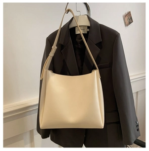 Gros plan d'un grand sac cabas en PU crème avec bandoulière réglable sur un cintre