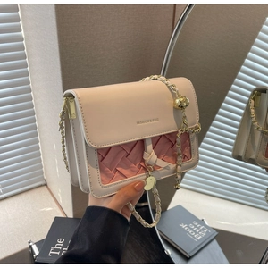 Détail du sac bandoulière bicolore avec texture tissée rose et chaîne dorée ajustable