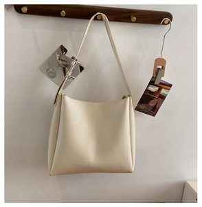 Vue détaillée d'un sac cabas en similicuir crème suspendu à un crochet en bois