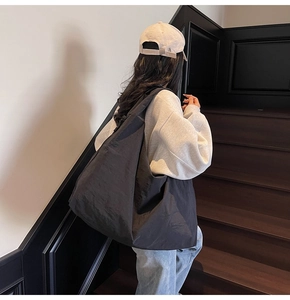 Close-up of a black slouchy canvas bag on a wooden staircase in a minimalist indoor setting