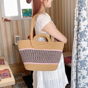 Close-up of a large woven straw beach tote bag with contrast stitching and shoulder strap