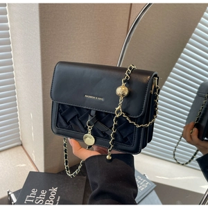 Détail du sac noir matelassé à chaîne avec breloques dorées et logo imprimé