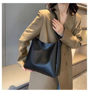 Sac fourre-tout minimaliste en cuir PU noir porté par un mannequin dans un bureau