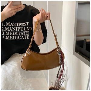 Close-up of brown semi-moon hobo bag with sleek faux leather texture and braided charm