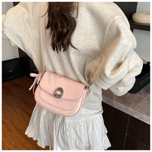Détail du sac de selle en cuir verni rose avec charm en perles et boucle métallique