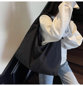 Detail of a large black slouchy canvas shoulder bag showing soft fabric texture and drape
