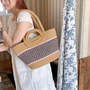 Detail of hand-woven straw tote bag with pink and black decorative stripe accents