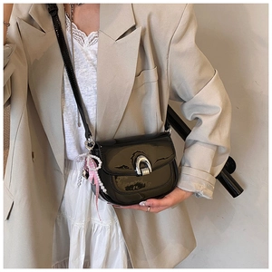 Détail du sac selle en cuir verni noir brillant avec boucle argentée et perles