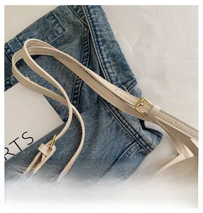 Detail of adjustable beige leather shoulder strap with gold buckle and fine stitching