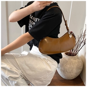 Detailed view of brown glossy leather hobo bag with a heart pendant and shoulder strap