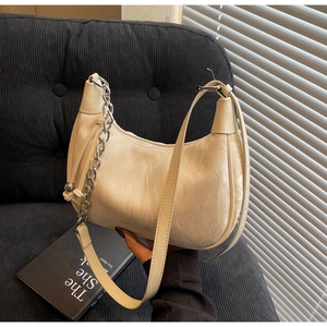 Detail of off-white hobo bag showing marble texture and silver chain strap on sofa