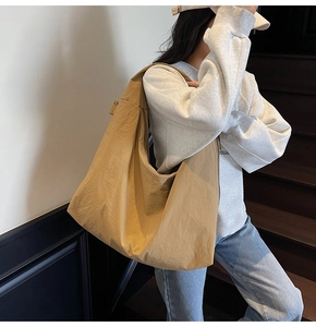 Detail of a khaki large-capacity canvas hobo bag on a wooden staircase with wide straps