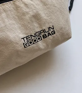 Gros plan sur un sac beige avec texture en nylon plissé et logo noir imprimé