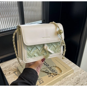 Détail du sac matelassé crème avec texture tissée verte et bandoulière chaîne dorée